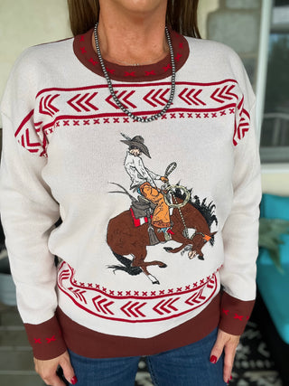 Person wearing a sweater with a cowboy graphic and red and brown patterns.