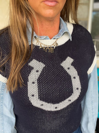 Person wearing a navy blue sweater with a horseshoe design.